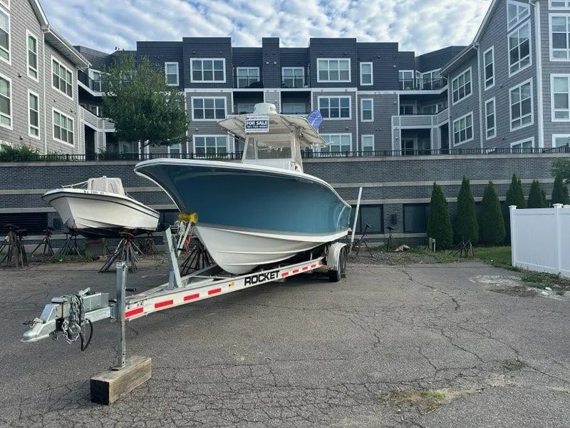 Slide: The Image of 2012 Onslow Bay 27 OE boat on trailer, parked in front of modern apartments. - 2