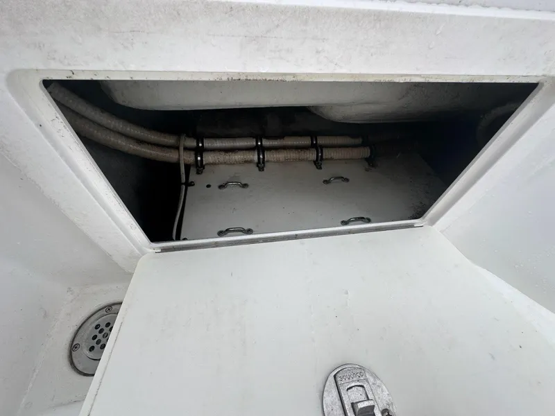Slide: The Image of Open storage compartment on a 2012 Onslow Bay 27 OE boat, showing interior pipes and fittings. - 22