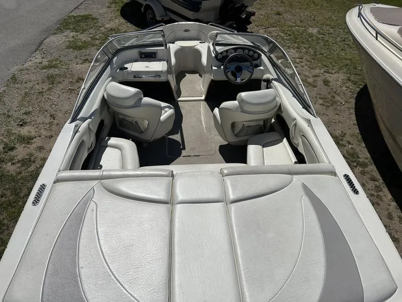 Slide: The Image of 2007 Stingray 210LR boat interior with white seating and steering wheel, parked on grass. - 13