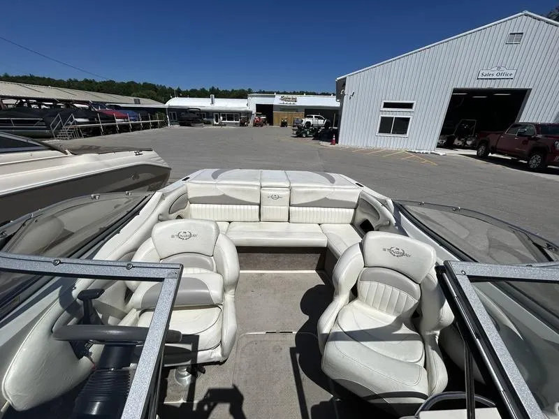 Slide: The Image of 2007 Stingray 210LR boat interior with white seating, parked near sales office. - 7