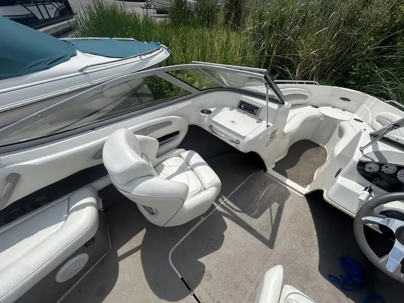 Slide: The Image of 2007 Stingray 210LR boat interior with white seating and dashboard, surrounded by greenery. - 9