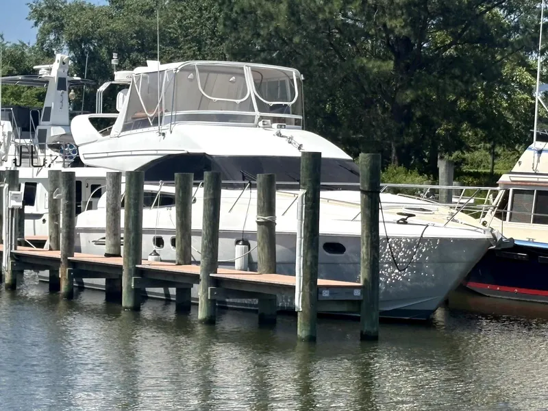 Slide: The Image of 2003 Princess 50 yacht docked at marina, surrounded by trees and calm water. - 2