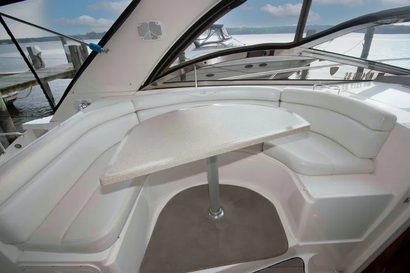 Slide: The Image of 2003 Regal Commodore 4260 yacht interior with white seating and table, docked by the water. - 10