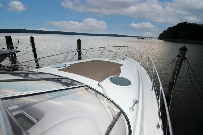 Slide: The Image of 2003 Regal Commodore 4260 yacht docked by serene waters under a cloudy sky. - 11