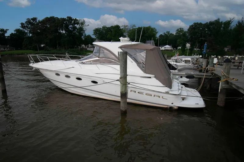 Slide: The Image of 2003 Regal Commodore 4260 yacht docked at a marina, surrounded by trees and calm water. - 3
