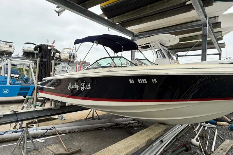 The Image of 2016 Chris-Craft Launch 22 boat on a lift, featuring a navy hull and canopy. - 1