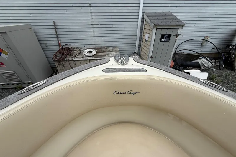 Slide: The Image of 2016 Chris-Craft Launch 22 boat interior with beige seating, docked near a shed. - 8
