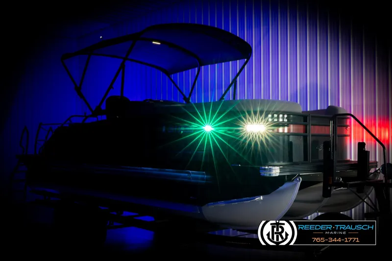 Slide: The Image of 2023 Barletta 21 UC pontoon boat with vibrant lights in a dimly lit showroom. - 4