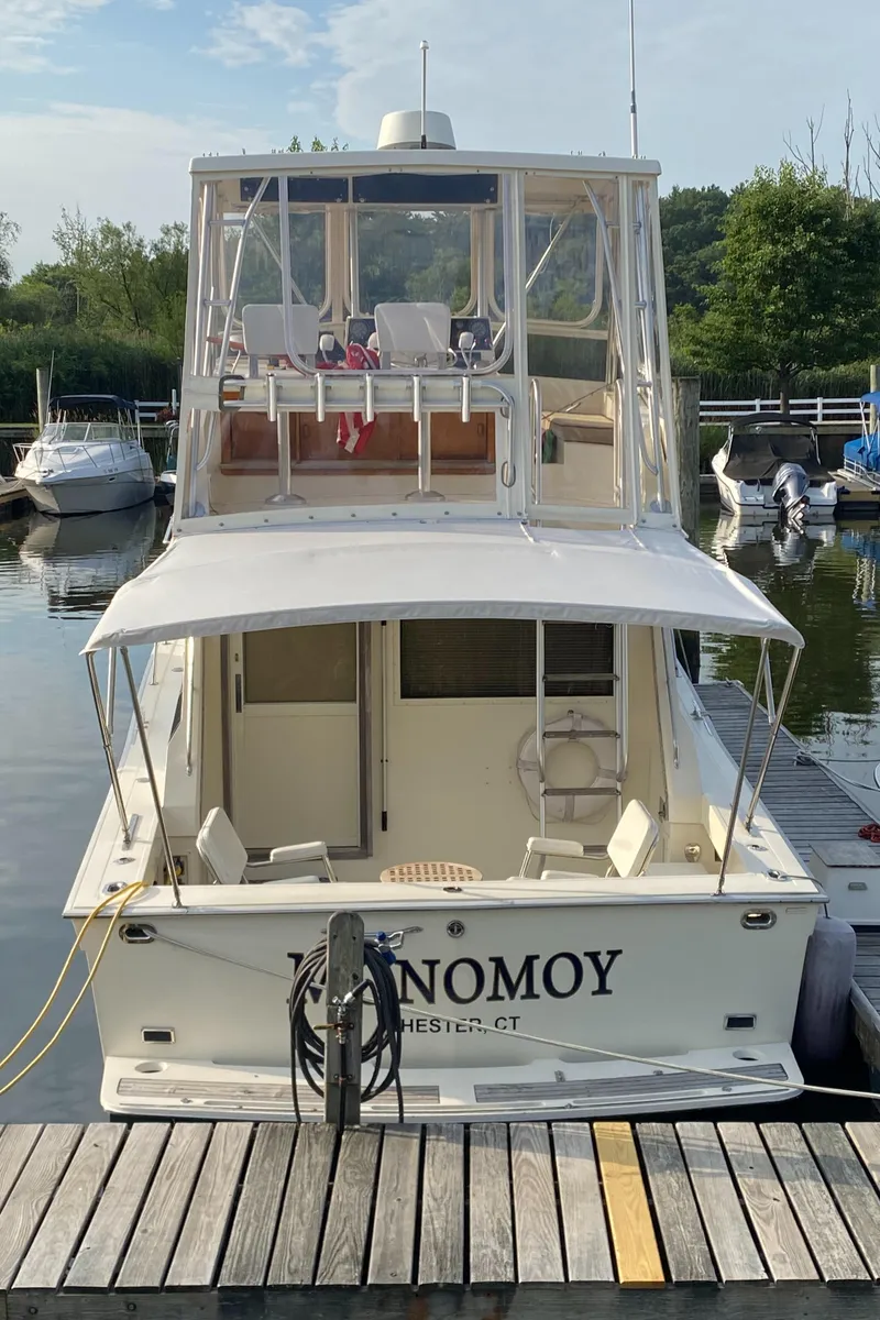 Slide: The Image of 1986 Viking 35 Convertible boat docked at a marina, rear view with upper deck seating. - 11