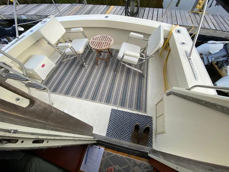 Slide: The Image of 1986 Viking 35 Convertible boat interior with chairs, table, and striped rug on deck. - 12