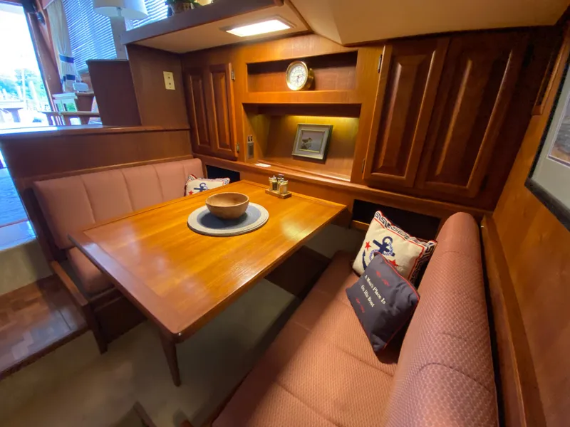 Slide: The Image of 1986 Viking 35 Convertible yacht interior with wooden dining area and nautical-themed cushions. - 25