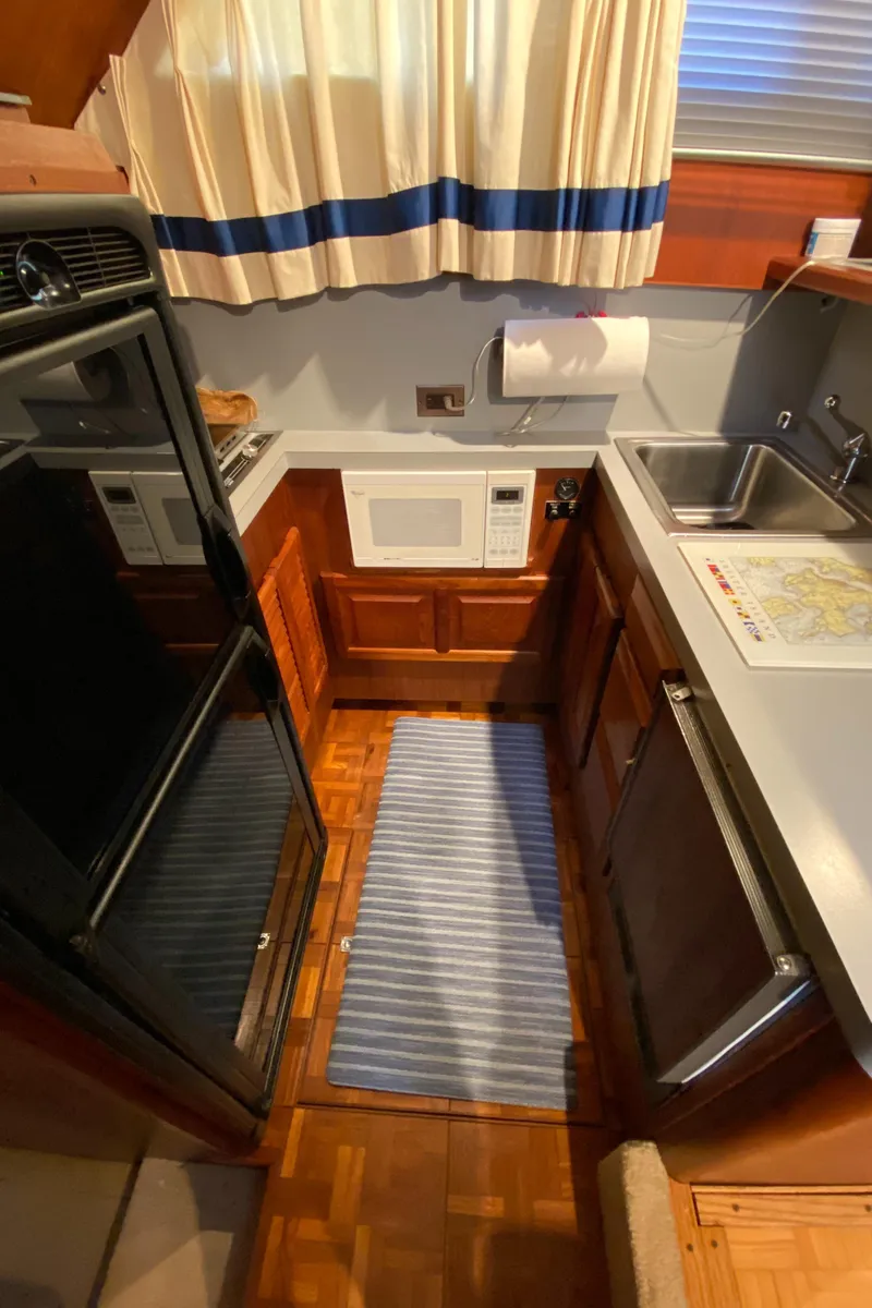 Slide: The Image of Compact kitchen in 1986 Viking 35 Convertible boat with appliances and striped rug. - 28