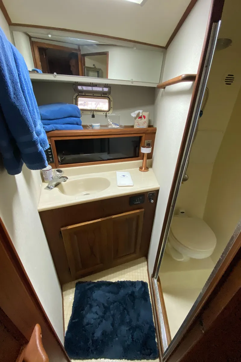 Slide: The Image of Compact bathroom in a 1986 Viking 35 Convertible yacht, featuring sink, mirror, and shower. - 30