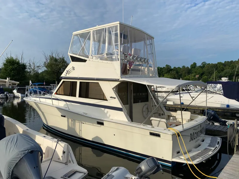 Slide: The Image of 1986 Viking 35 Convertible boat docked at marina, clear sky background. - 4