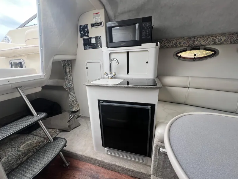 Slide: The Image of Interior of 2000 Crownline 242 CR boat with kitchenette, microwave, and seating area. - 14