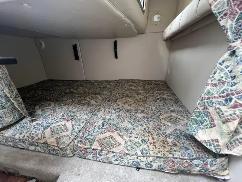 Slide: The Image of Crownline 242 CR 2000 cabin interior with patterned cushions and compact sleeping area. - 16