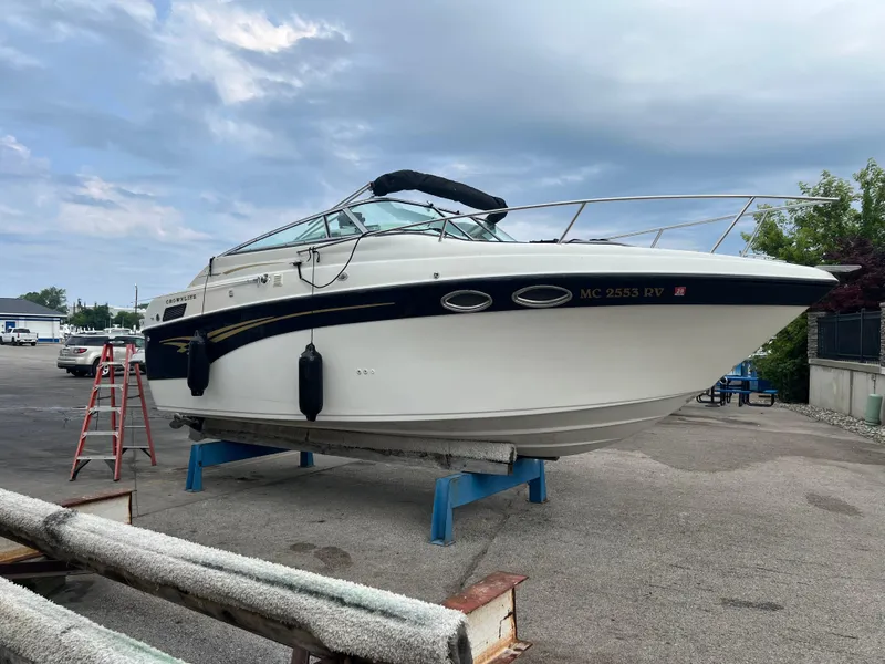 Slide: The Image of 2000 Crownline 242 CR boat on stands, with a cloudy sky background. - 2
