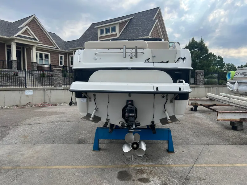 Slide: The Image of Crownline 242 CR 2000 boat on stand, residential background, overcast sky. - 3