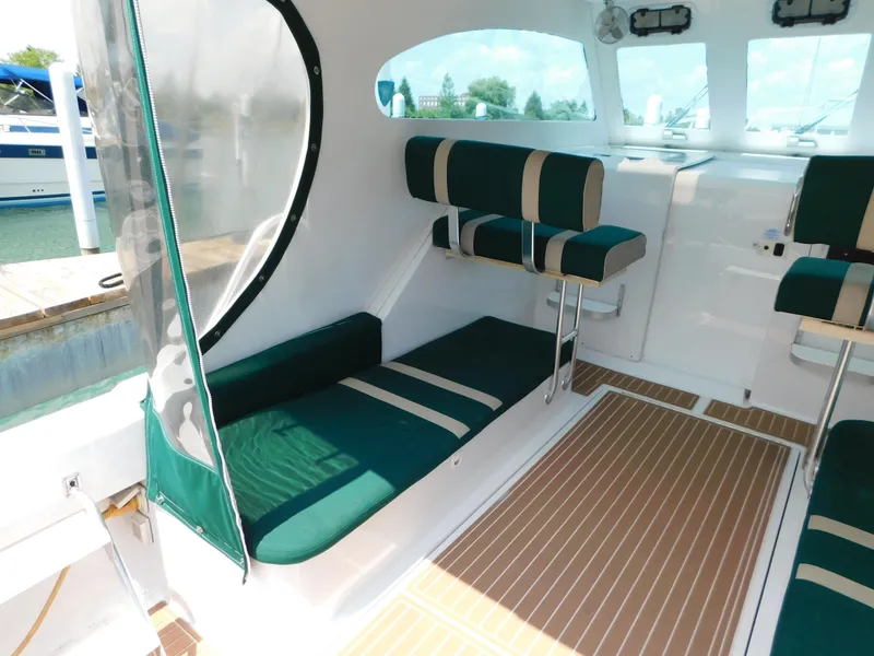 Slide: The Image of 1999 Mainship Pilot 30 interior with green seating and wood-patterned flooring. - 14
