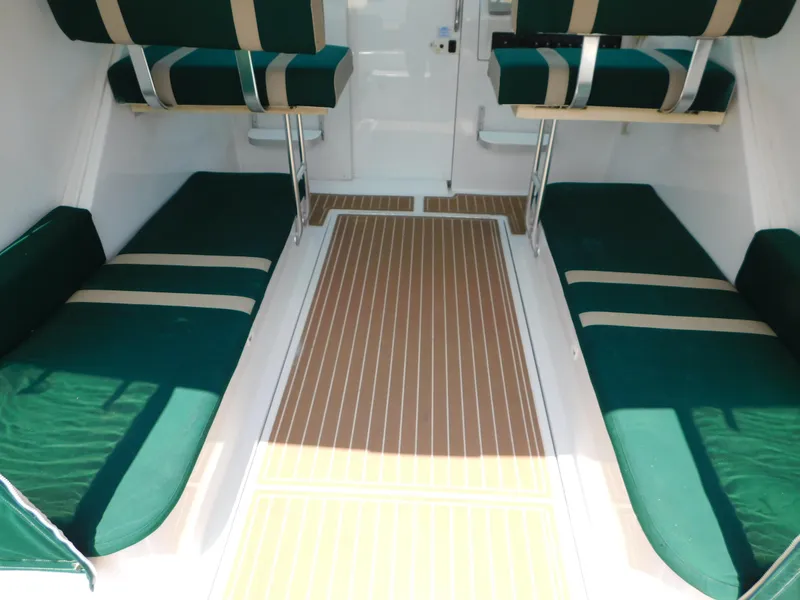 Slide: The Image of 1999 Mainship Pilot 30 interior with green cushioned seating and wood-patterned flooring. - 15