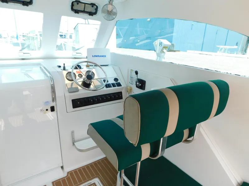 Slide: The Image of 1999 Mainship Pilot 30 helm with green seating and navigation equipment. - 17