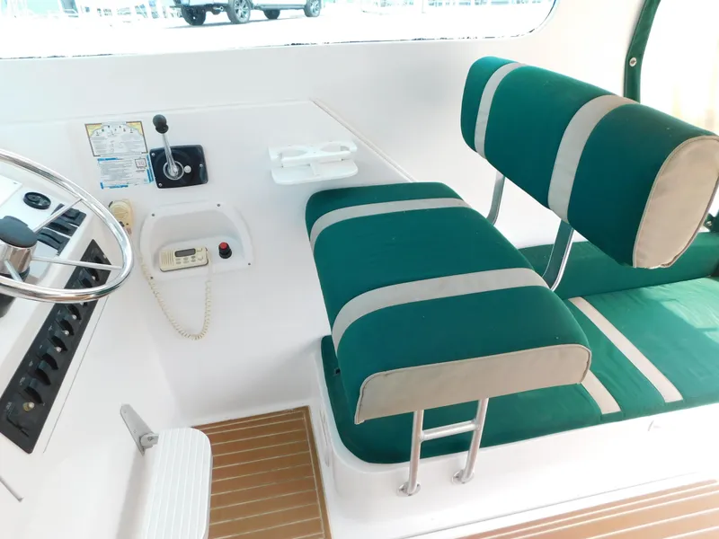 Slide: The Image of 1999 Mainship Pilot 30 cockpit with green and white seating, steering wheel, and control panel. - 18