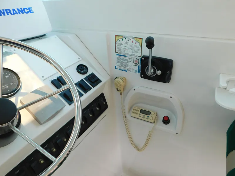 Slide: The Image of 1999 Mainship Pilot 30 helm with steering wheel, controls, and communication equipment. - 19