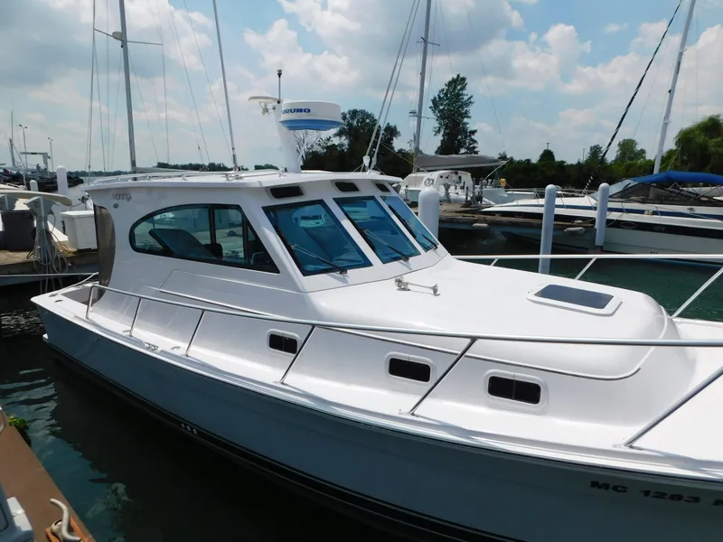 Slide: The Image of 1999 Mainship Pilot 30 boat docked at marina under cloudy sky. - 3