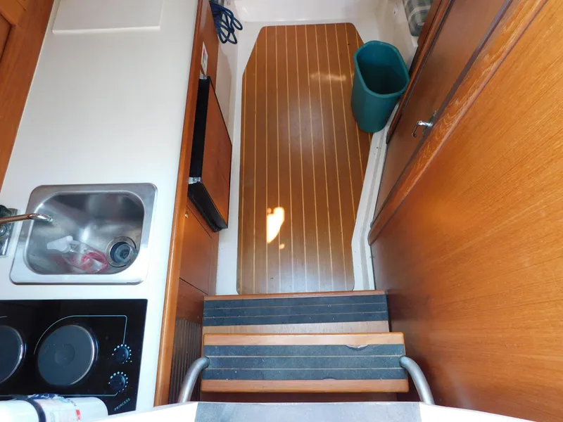 Slide: The Image of 1999 Mainship Pilot 30 interior with sink, stove, and wooden cabinetry. - 35