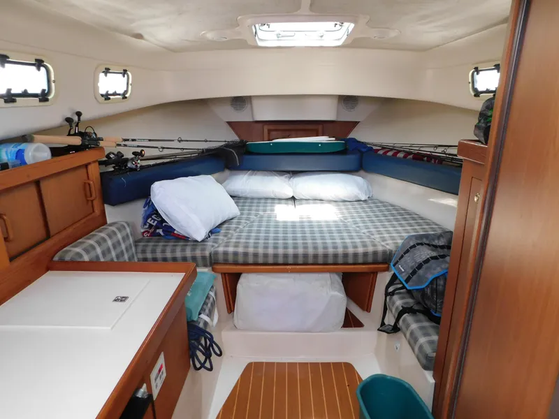 Slide: The Image of 1999 Mainship Pilot 30 cabin interior with bed, fishing rods, and storage. - 37