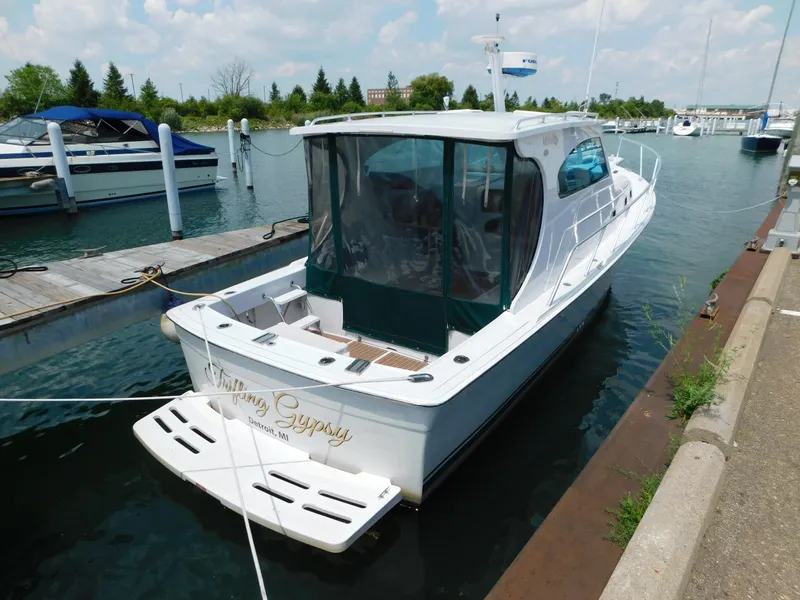 Slide: The Image of 1999 Mainship Pilot 30 docked at marina, featuring sleek design and covered cockpit. - 4