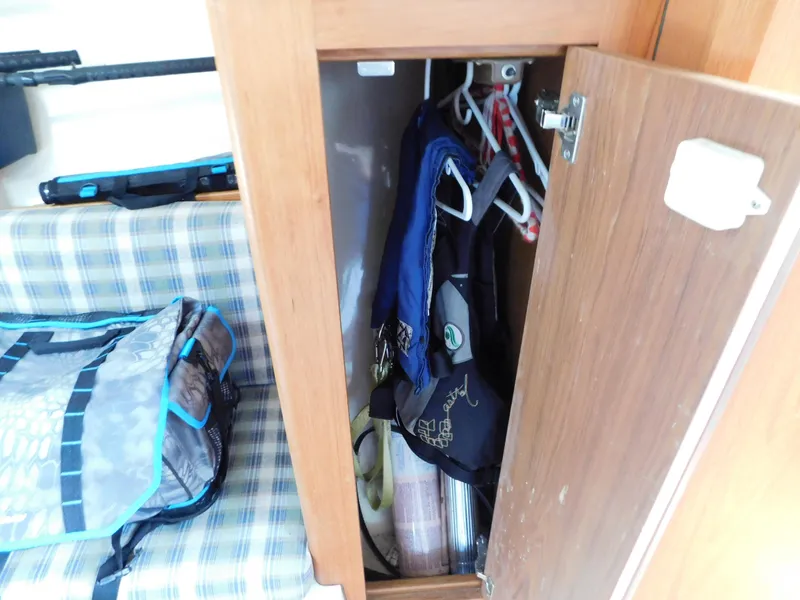 Slide: The Image of 1999 Mainship Pilot 30 interior with open wooden cabinet and plaid seating. - 42