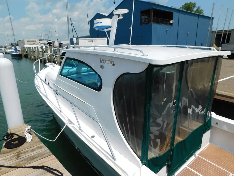 Slide: The Image of 1999 Mainship Pilot 30 docked at marina, featuring sleek design and enclosed cockpit. - 7