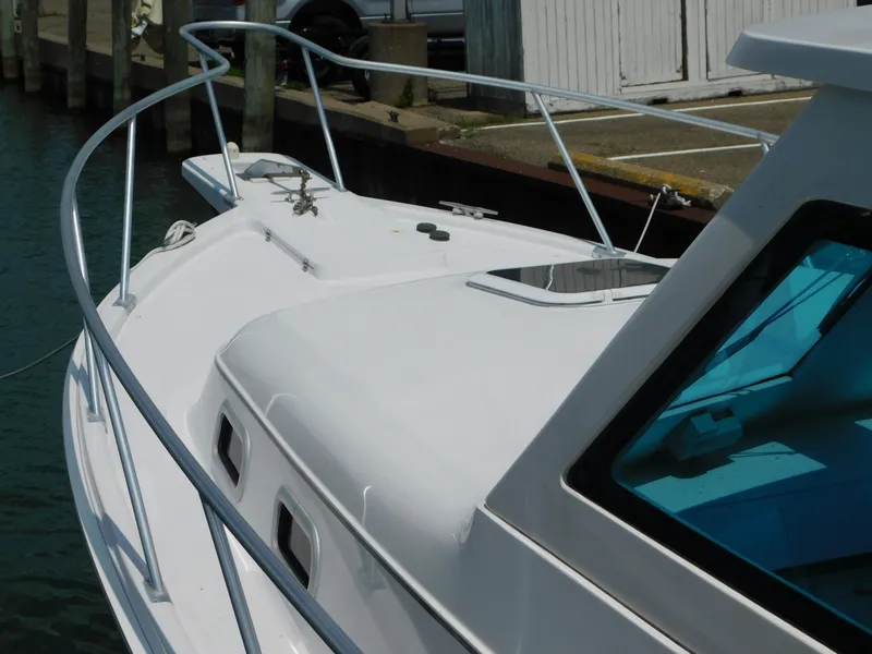 Slide: The Image of 1999 Mainship Pilot 30 boat docked, showcasing sleek white deck and railing. - 8