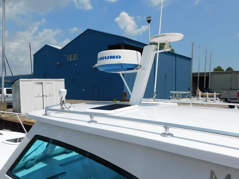 Slide: The Image of 1999 Mainship Pilot 30 boat docked near blue industrial buildings under a cloudy sky. - 9