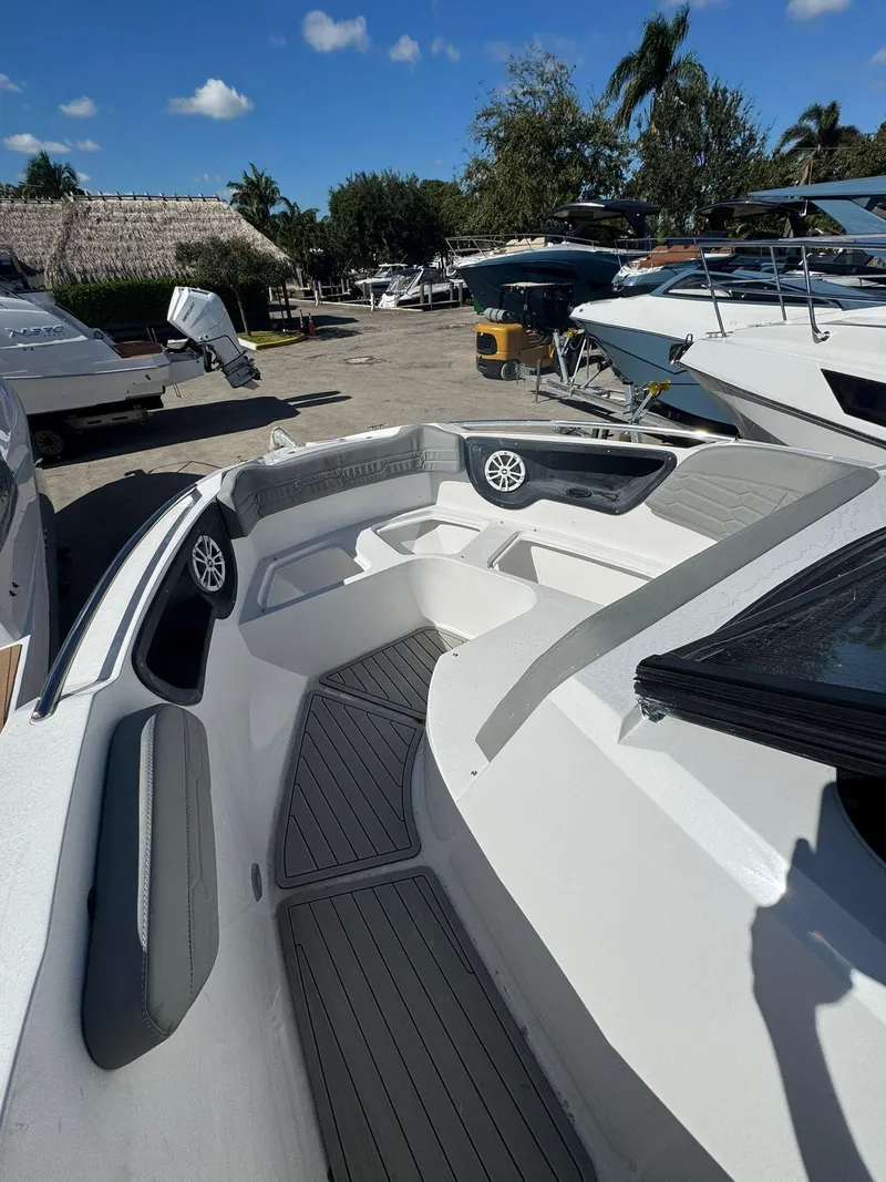 Slide: The Image of 2025 NX Boats NX280 XTREME interior with seating and speakers, docked under a clear sky. - 11