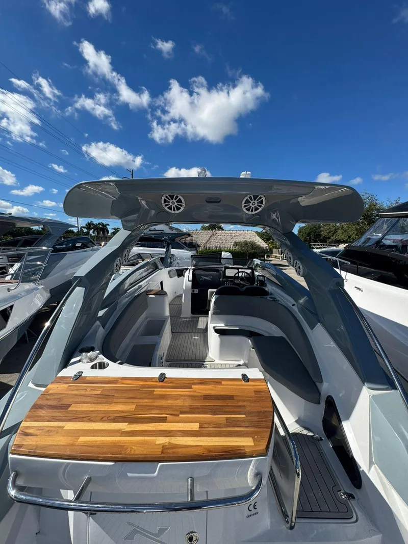 Slide: The Image of 2025 NX Boats NX280 XTREME with sleek design and wooden deck under a clear blue sky. - 7