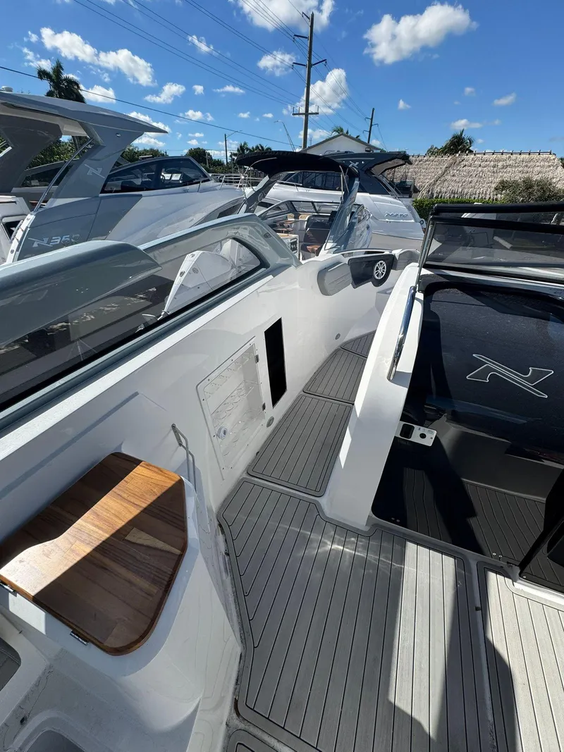 Slide: The Image of 2025 NX Boats NX280 XTREME interior with sleek design and wooden accents under a clear blue sky. - 9