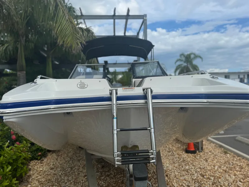 Slide: The Image of 2017 Starcraft 230 OB SCX EXT boat on trailer, surrounded by palm trees and gravel. - 5