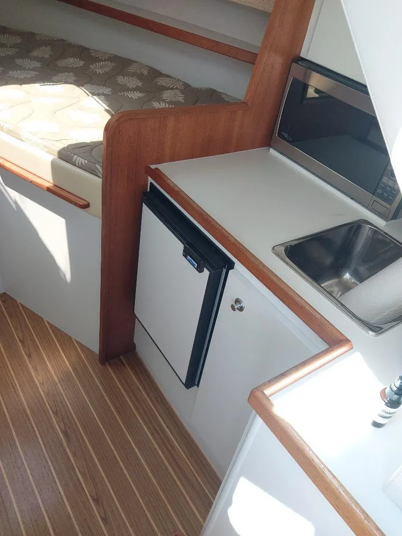 Slide: The Image of 2006 Tiara Yachts 2900 Coronet interior with kitchenette, bed, and wood flooring. - 7