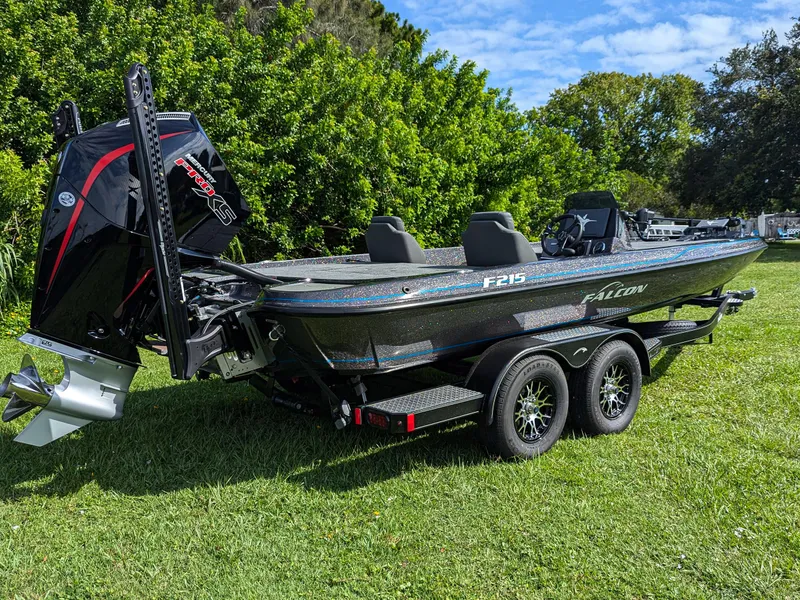 The Image of 2026 Falcon F215 boat on trailer, parked on grass, with lush greenery background. - 0