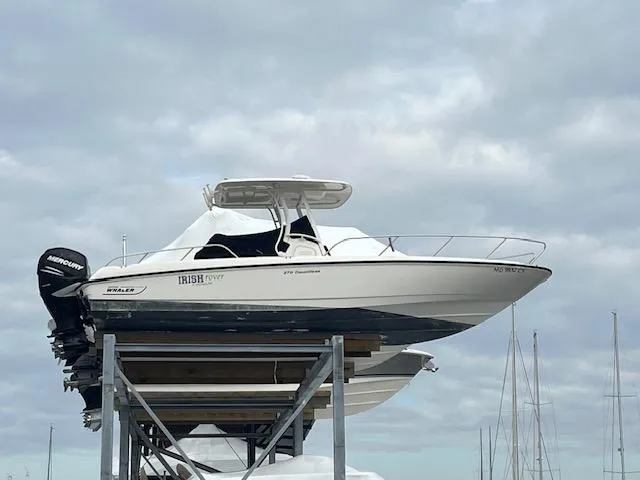 The Image of 2014 Boston Whaler 270 Dauntless boat on elevated storage, cloudy sky background. - 0