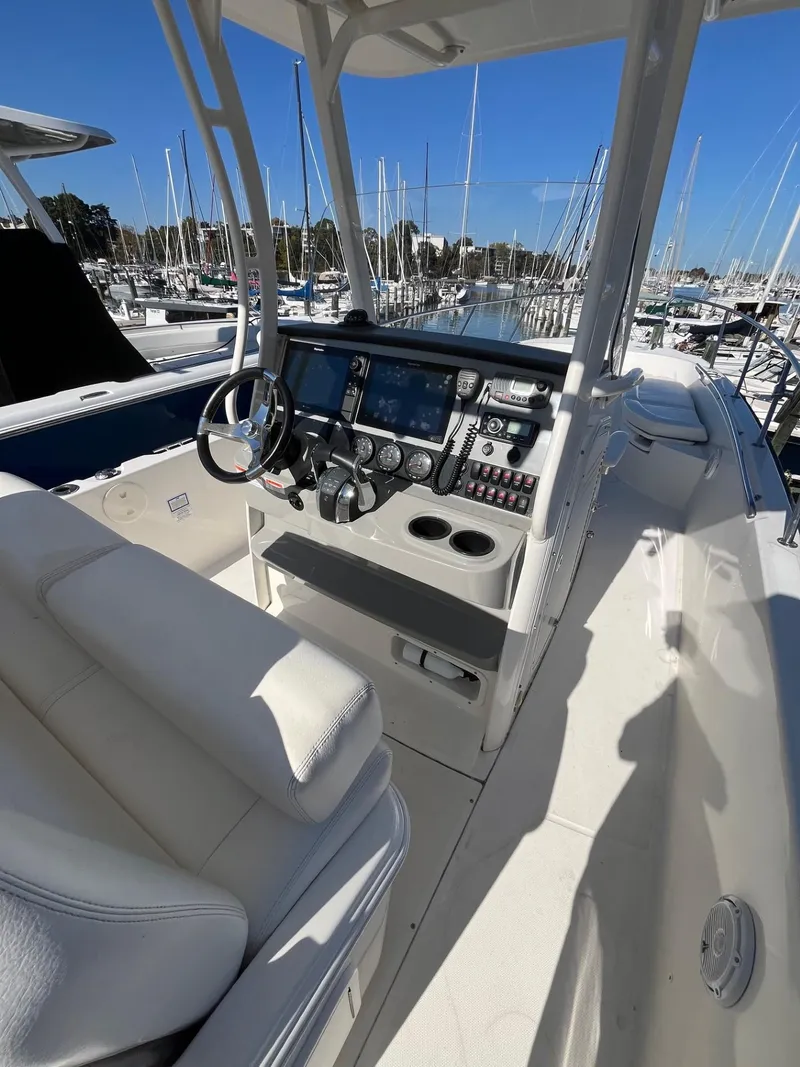 Slide: The Image of 2014 Boston Whaler 270 Dauntless boat interior with helm and seating in marina. - 16