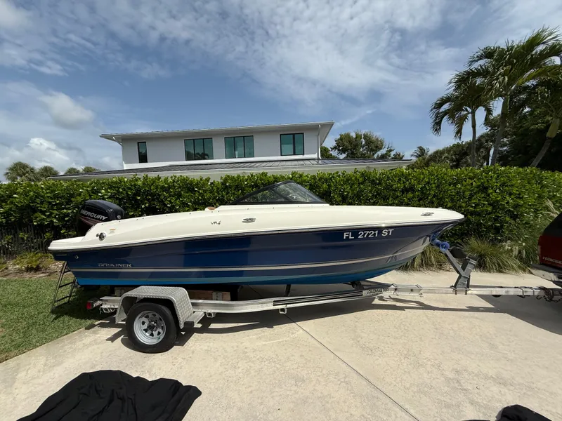 The Image of 2019 Bayliner VR4 Bowrider OB on trailer, parked in driveway with lush greenery background. - 0