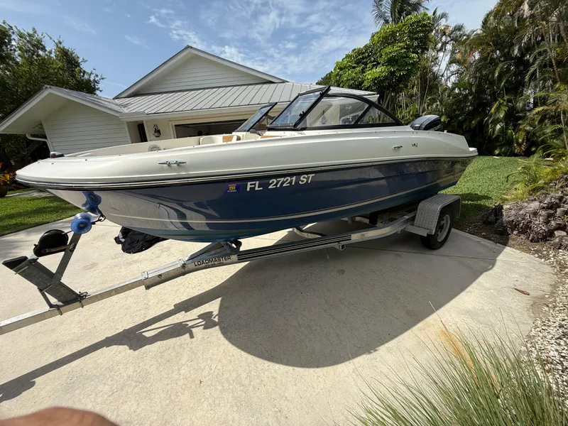 Slide: The Image of 2019 Bayliner VR4 Bowrider OB on trailer in driveway, surrounded by greenery. - 1