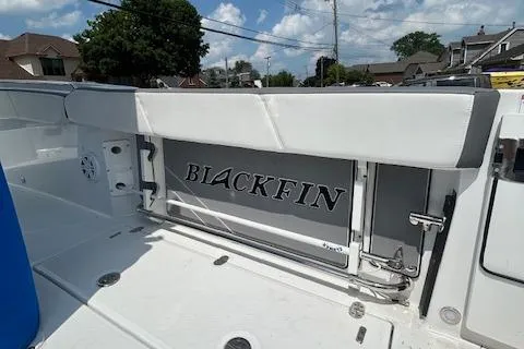 Slide: The Image of 2019 Blackfin 242 CC boat interior with logo, white seating, and clear sky background. - 12