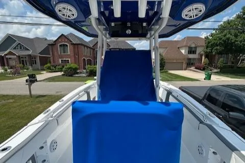 Slide: The Image of 2019 Blackfin 242 CC boat with blue cover, parked in suburban neighborhood. - 14