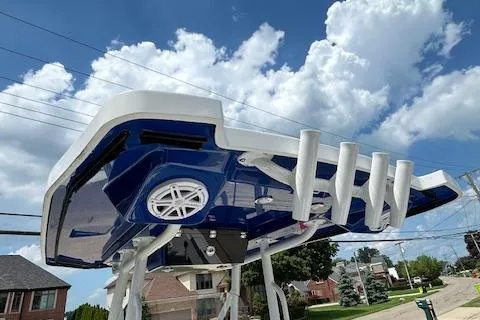 Slide: The Image of 2019 Blackfin 242 CC boat with blue hull, rod holders, and speaker, under a clear sky. - 19