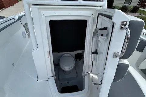 Slide: The Image of 2019 Blackfin 242 CC boat interior with open door revealing compact marine toilet. - 23