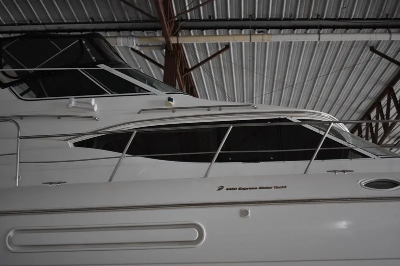 Slide: The Image of 2000 Cruisers Yachts 4450 Express Motoryacht in storage, side view under metal roof. - 8